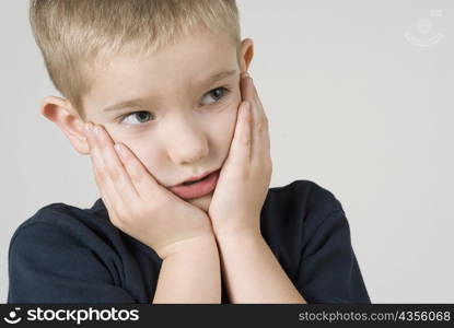 Close-up of a boy thinking with his head in his hands