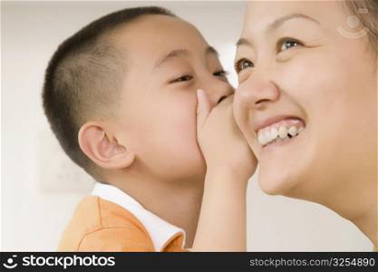 Close-up of a boy whispering to his mother
