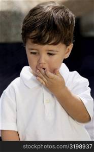 Close-up of a boy with his hand covered his mouth