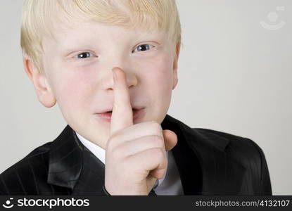 Close-up of a boy with silence gesture