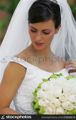 Close-up of a bride holding a bouquet of flowers and looking down