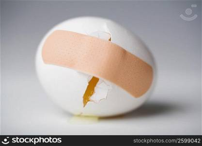 Close-up of a broken egg with an adhesive bandage on it