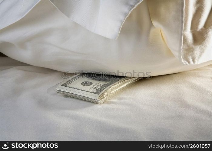 Close-up of a bundle of one hundred dollar bills on the bed
