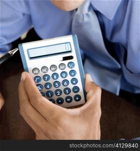 Close-up of a businessman&acute;s hand holding a calculator