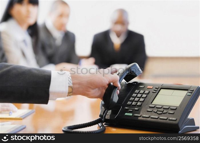 Close-up of a businessman&acute;s hand holding a conference phone receiver