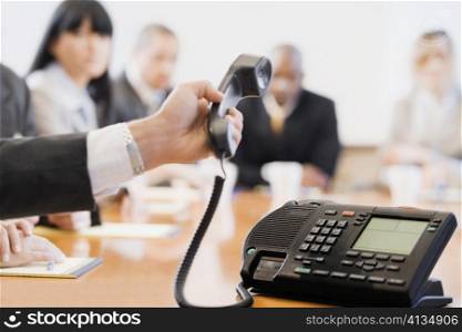 Close-up of a businessman&acute;s hand holding a conference phone receiver