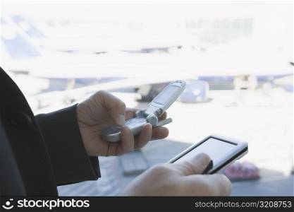 Close-up of a businessman&acute;s hands using a mobile phone and a personal data assistant