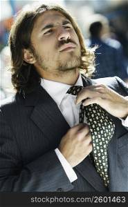 Close-up of a businessman adjusting his tie