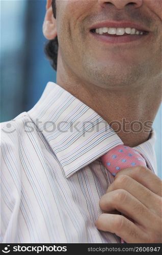 Close-up of a businessman adjusting his tie and smiling