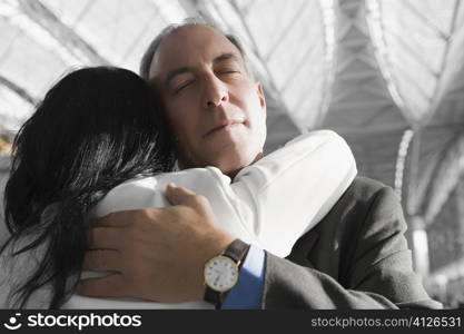 Close-up of a businessman and a businesswoman hugging each other at an airport