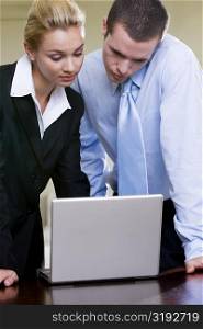 Close-up of a businessman and a businesswoman looking at a laptop