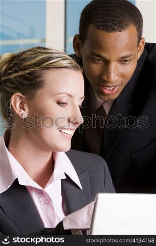 Close-up of a businessman and a businesswoman looking at a laptop