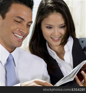 Close-up of a businessman and a businesswoman reading a book