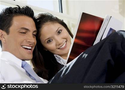 Close-up of a businessman and a businesswoman reading a magazine
