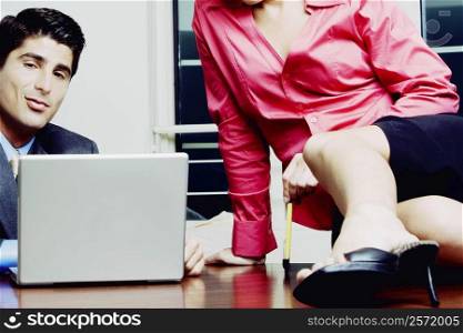 Close-up of a businessman and a businesswoman sitting on a desk