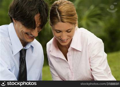 Close-up of a businessman and a businesswoman smiling in the park
