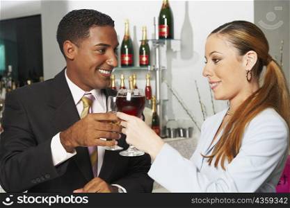 Close-up of a businessman and a businesswoman toasting with wine glasses