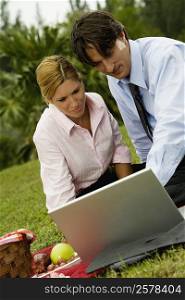Close-up of a businessman and a businesswoman working on a laptop in the park