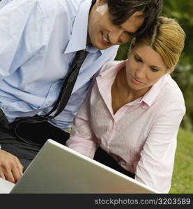 Close-up of a businessman and a businesswoman working on a laptop in the park