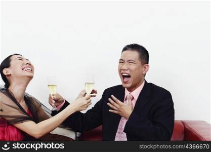 Close-up of a businessman and a mid adult woman holding glasses of champagne and laughing together