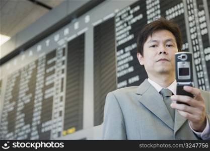 Close-up of a businessman at an airport holding a mobile phone