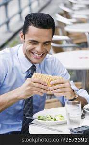 Close-up of a businessman eating a cheese sandwich and smiling