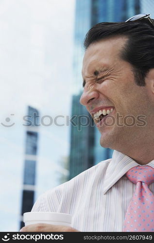 Close-up of a businessman holding a disposable cup and smiling