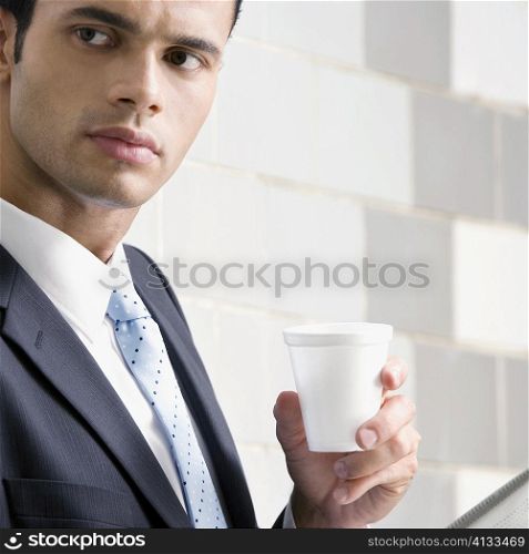 Close-up of a businessman holding a disposable cup and thinking