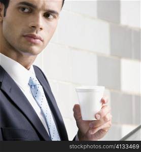 Close-up of a businessman holding a disposable cup and thinking