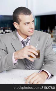 Close-up of a businessman holding a glass of cocktail in a bar