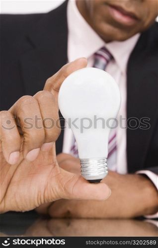 Close-up of a businessman holding a light bulb