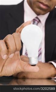 Close-up of a businessman holding a light bulb
