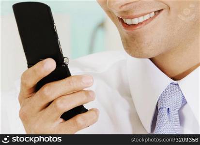 Close-up of a businessman holding a mobile phone and smiling