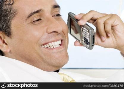 Close-up of a businessman holding a mobile phone smiling