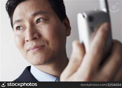 Close-up of a businessman holding a mobile phone thinking