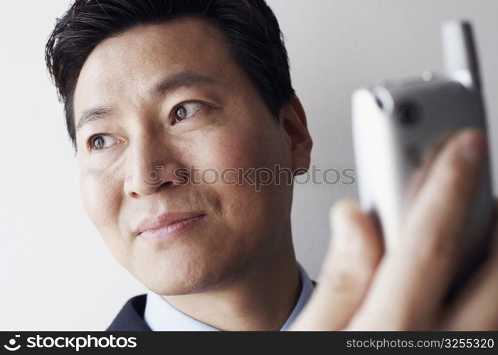 Close-up of a businessman holding a mobile phone thinking