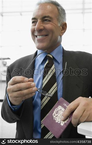 Close-up of a businessman holding an eyeglasses and a passport