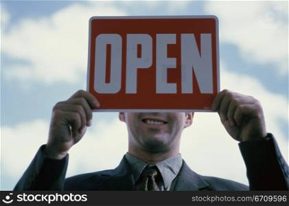 Close-up of a businessman holding an open sign
