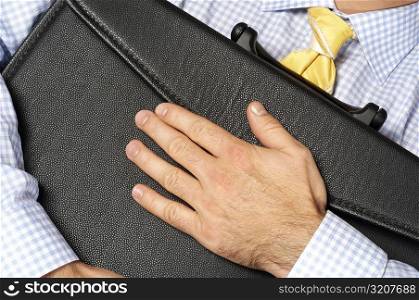 Close-up of a businessman hugging his briefcase