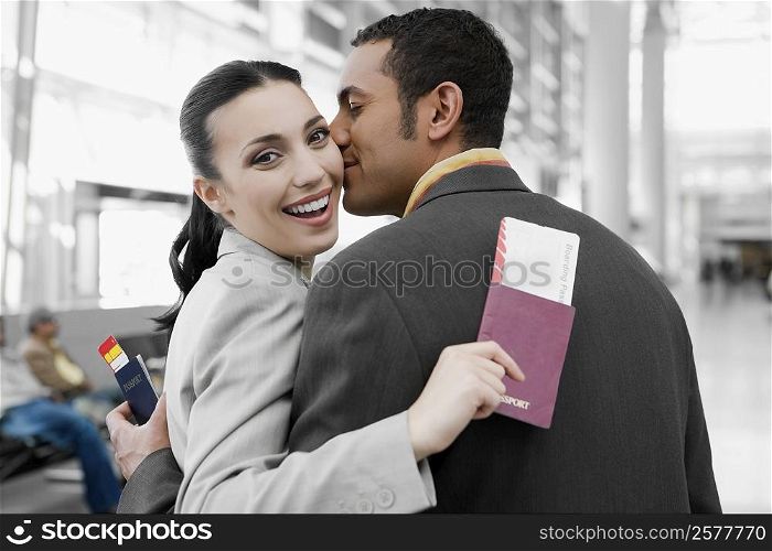 Close-up of a businessman kissing a businesswoman at an airport