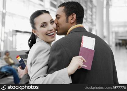 Close-up of a businessman kissing a businesswoman at an airport