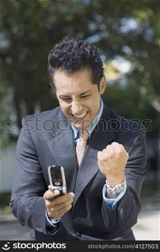 Close-up of a businessman looking at a mobile phone and making a fist
