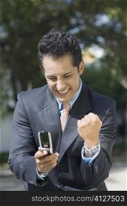Close-up of a businessman looking at a mobile phone and making a fist