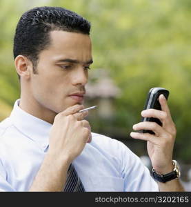 Close-up of a businessman looking at a personal data assistant and thinking