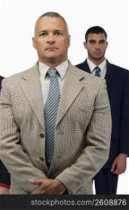 Close-up of a businessman looking serious with two businessmen standing behind him