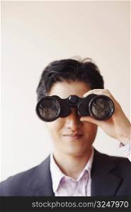 Close-up of a businessman looking through a pair of binoculars