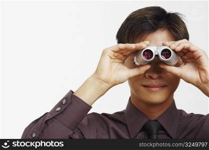Close-up of a businessman looking through a pair of binoculars