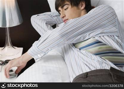 Close-up of a businessman lying on the bed and holding a mobile phone