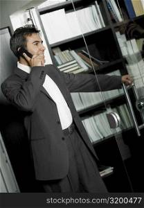 Close-up of a businessman opening a glass door and talking on a mobile phone
