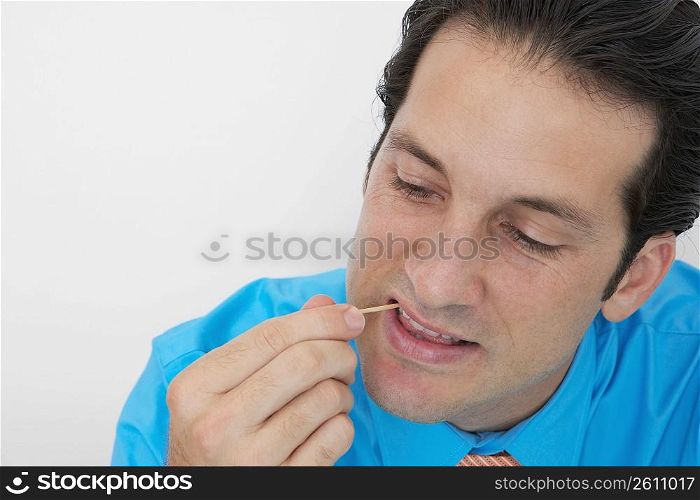 Close-up of a businessman picking his teeth in an office